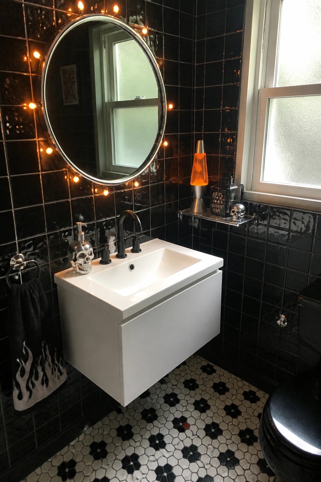 A bathroom with glossy black wall tiles, a white floating sink, round mirror, black faucet, skull soap dispenser, lava lamp, and black and white hexagonal floor tiles.