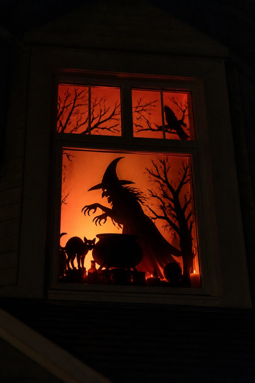 Witch silhouette with cauldron, black cat, crow, and trees in orange window glow