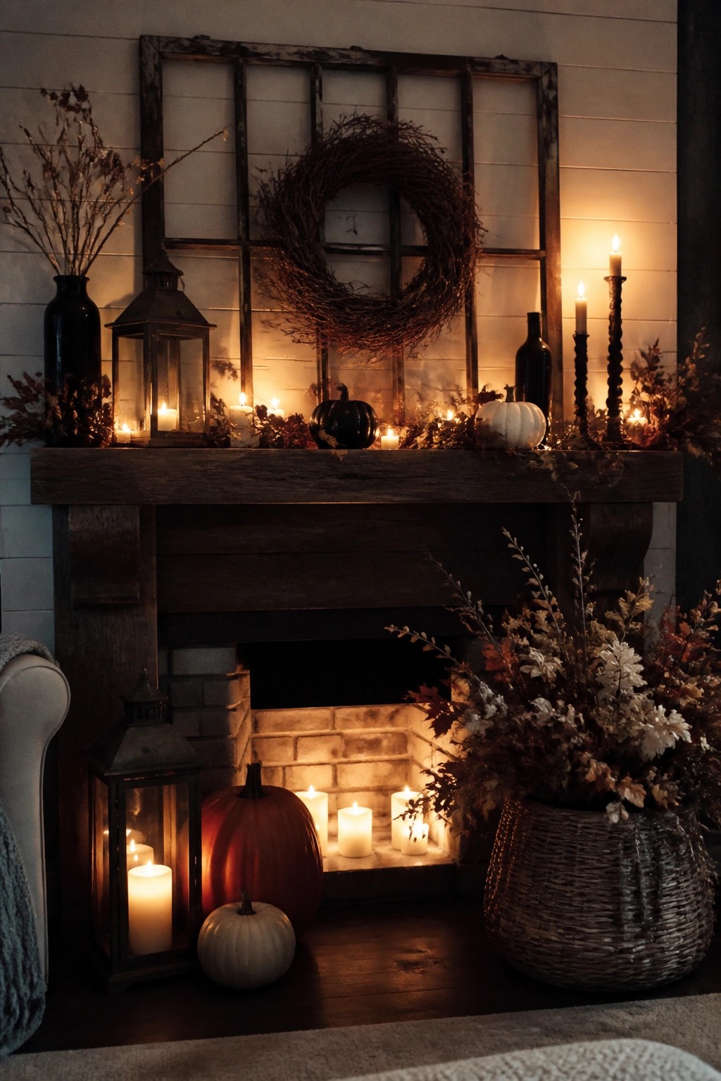 Cozy autumn mantel with glowing candles, pumpkins, lanterns, wreath, and dried florals.