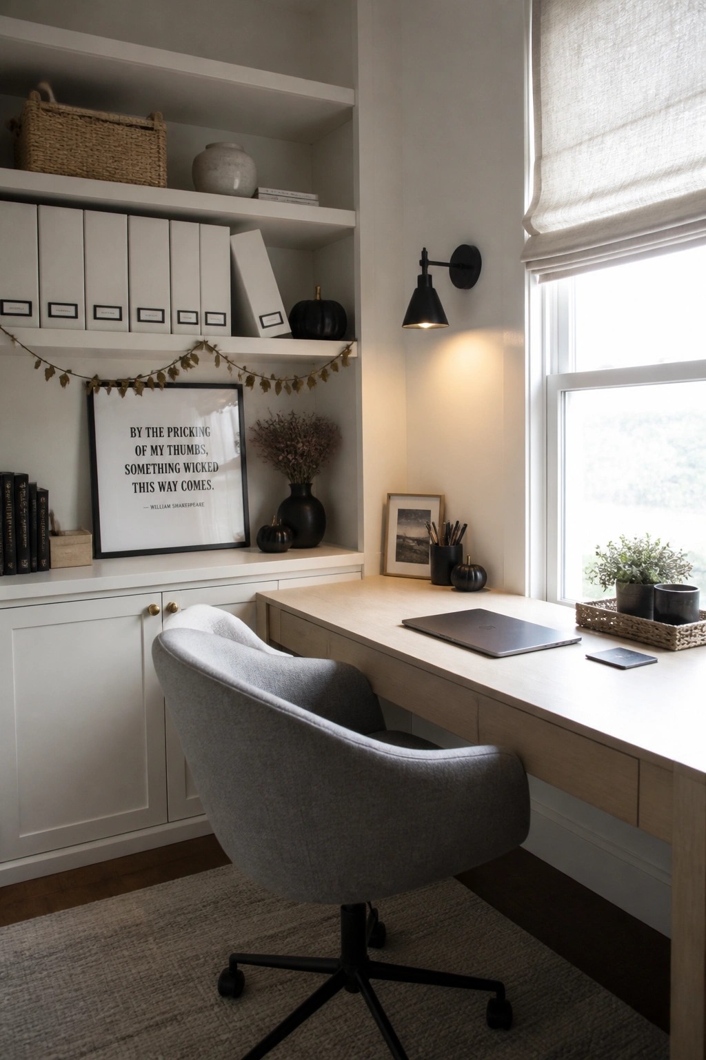 A home office with a light wood desk, gray upholstered chair on wheels, white built-in shelves, and small black pumpkins placed among books and decor.