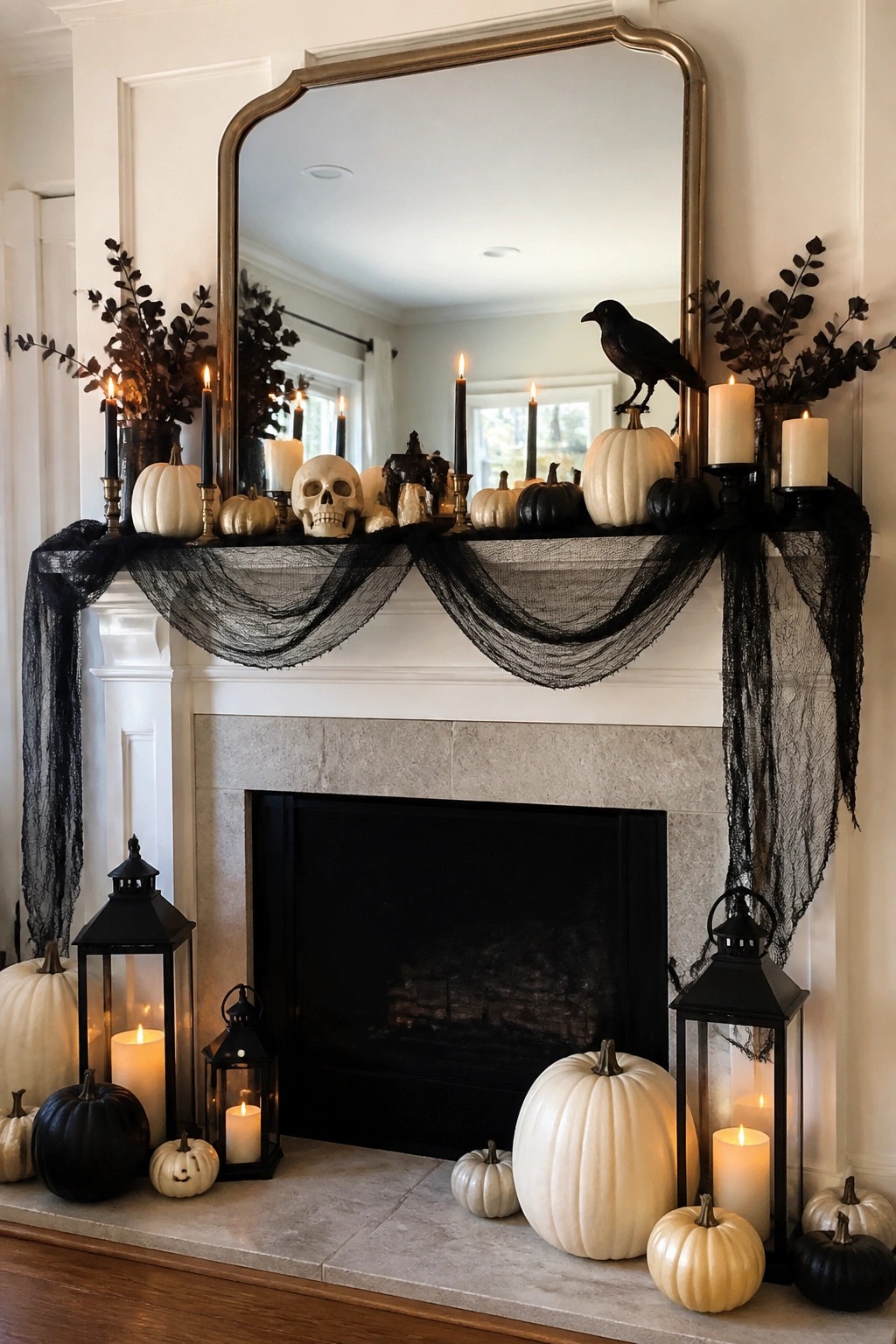 White fireplace mantel styled for Halloween with white pumpkins, a skull, a black crow, black candles, and black mesh garland.