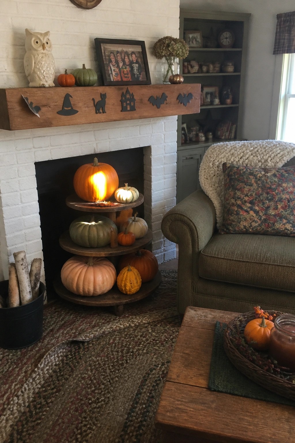 A white brick fireplace mantel with a wooden beam holding black Halloween silhouettes and small pumpkins.