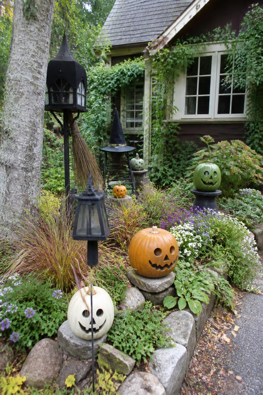 Halloween garden with carved pumpkins, black lanterns, witch hat, and broom.