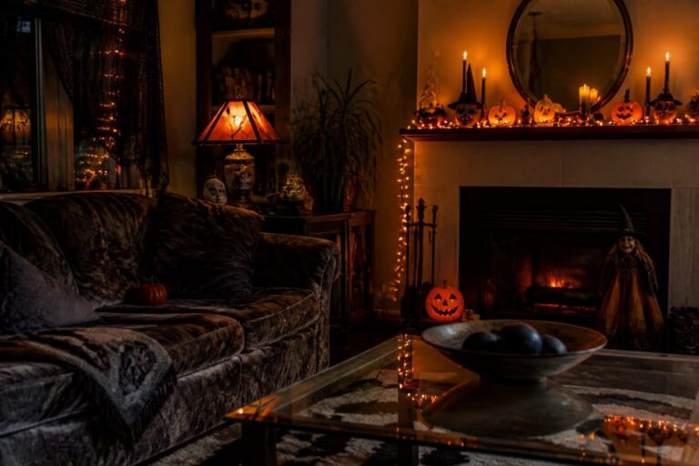 Living room fireplace mantel styled for Halloween with a carved jack o lantern, multiple lit candles, and dark garland across the brick surround.