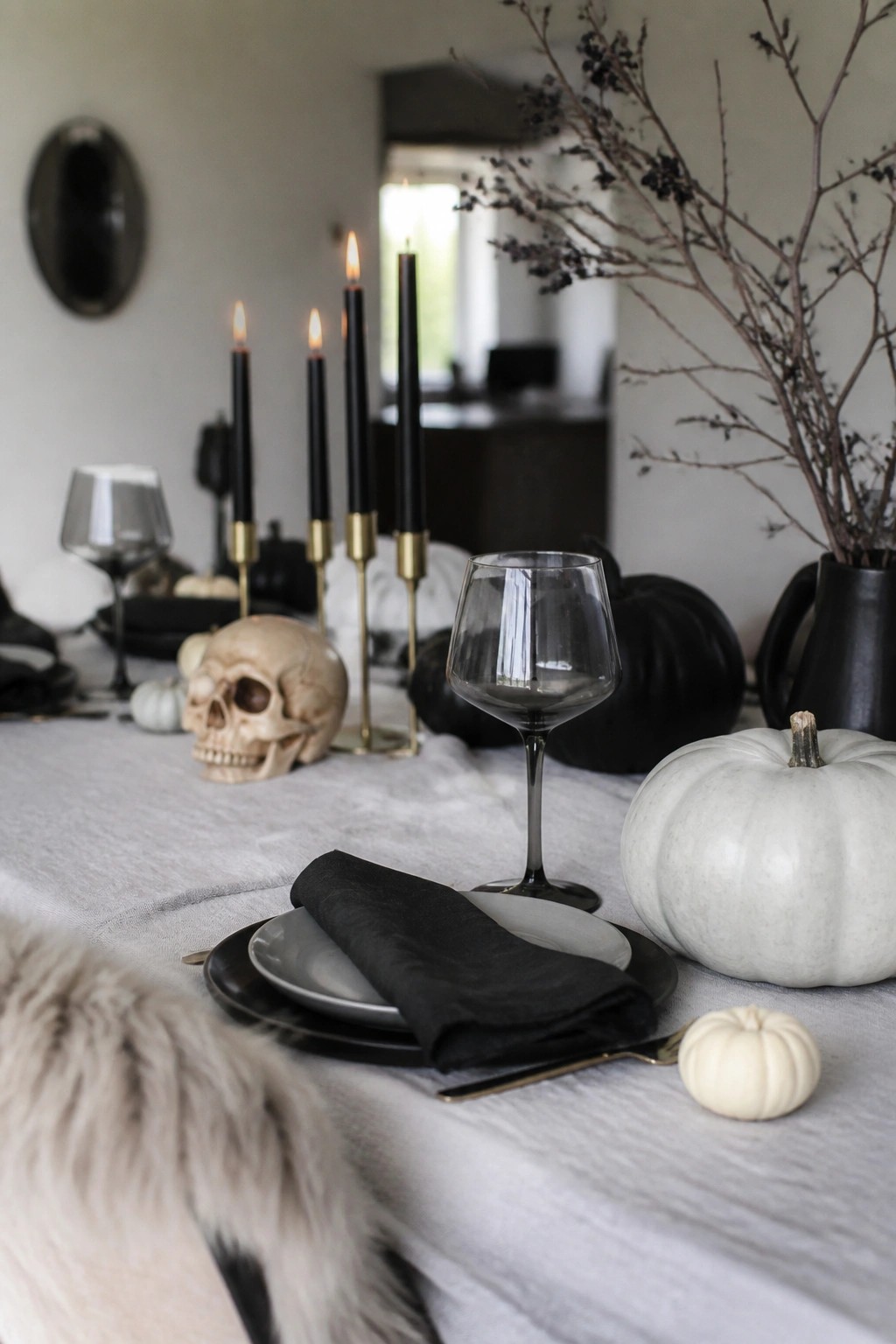 Elegant Halloween table with black candles, skull, white pumpkins, and linen runner