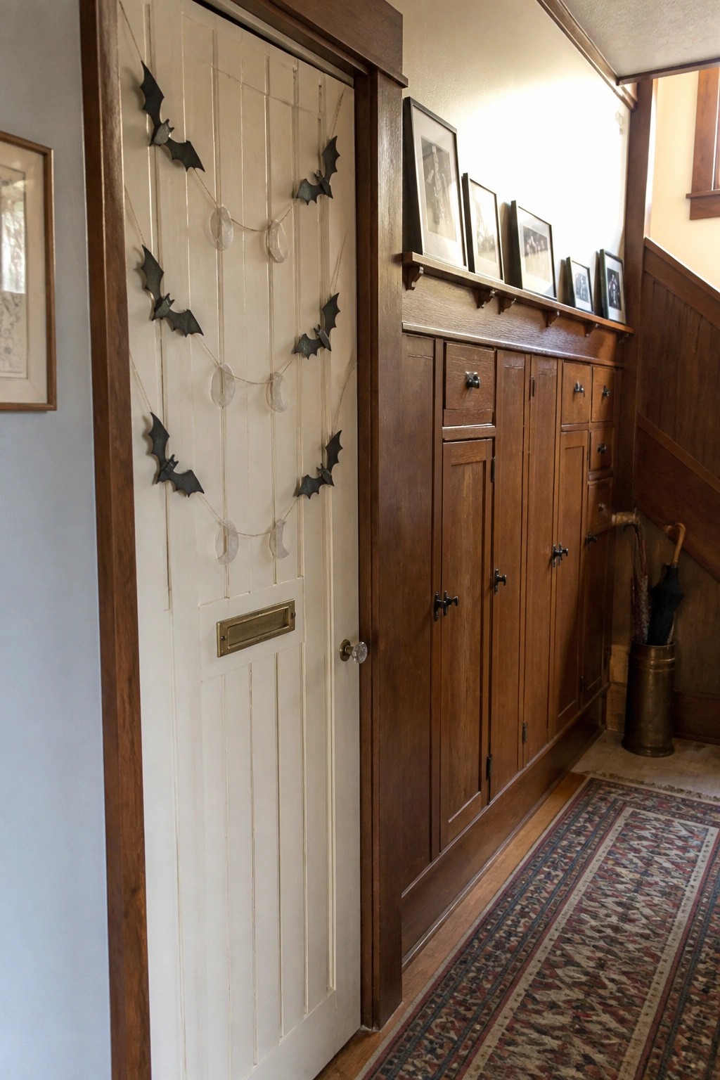 A white paneled interior door decorated with black bat and crescent moon garlands next to wooden built-in cabinets.