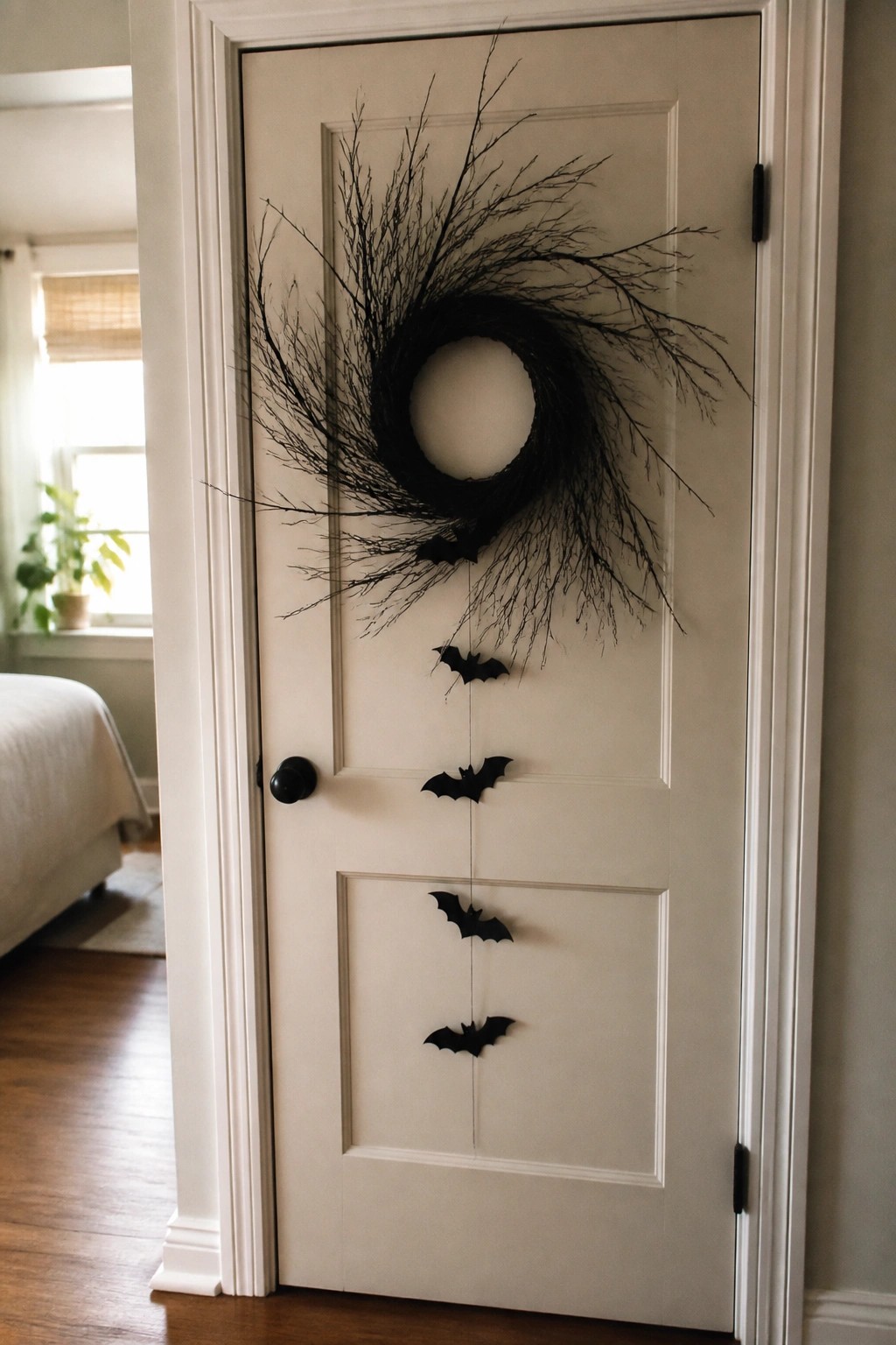 White interior door with a large black twig wreath and black bats hanging in a vertical line.