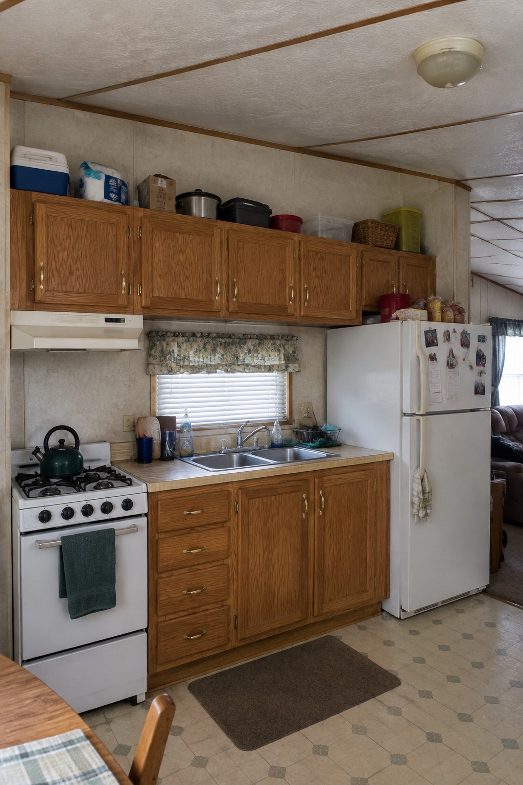 Before-and-after makeover image of a trailer kitchen updated with wood upper and lower cabinets, a stove, sink, and refrigerator.